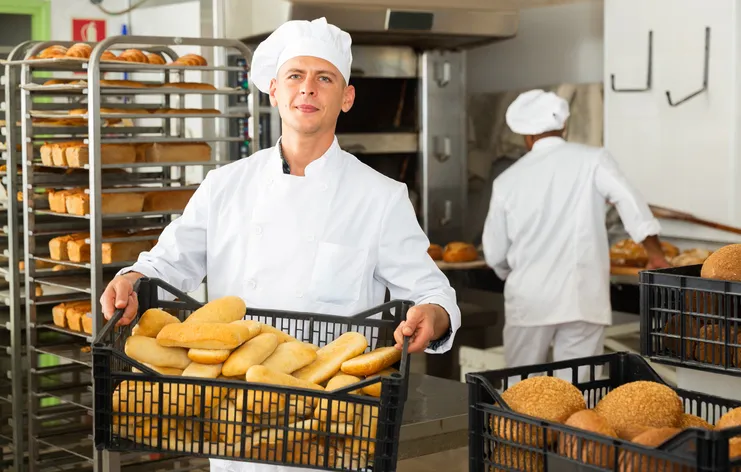 Franchise owner holding freshly baked bread in a Bakers Delight store